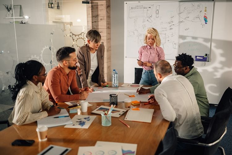 Teammeeting im modernen Büro – mehrere Personen arbeiten gemeinsam an einer Marketingstrategie und besprechen Ideen am Konferenztisch.